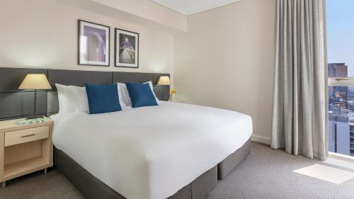 a large bed in a hotel room with a window at Oaks Brisbane Festival Suites in Brisbane