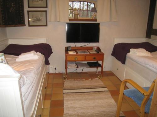 a bedroom with two beds and a desk with a tv at Mariehem Logi in Sjöbo