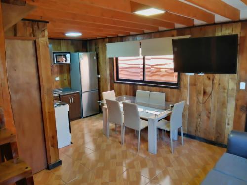 a dining room with a table and chairs and a television at CABAÑAS _EL NATIVO in Choshuenco