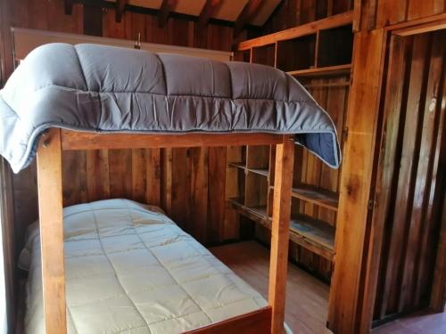 a bunk bed in a log cabin with a mattress at CABAÑAS _EL NATIVO in Choshuenco