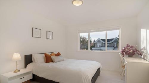 Habitación blanca con cama y ventana en 温西区豪华别墅附有按摩浴缸钢琴，接近机场downtown en Vancouver