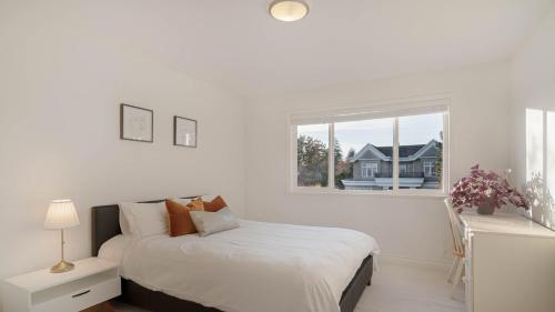 una camera da letto bianca con un letto e una finestra di 温西区豪华别墅附有按摩浴缸钢琴，接近机场downtown a Vancouver