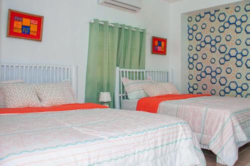 two beds with red and white sheets in a bedroom at D´ Yoko Village´s in Pedernales