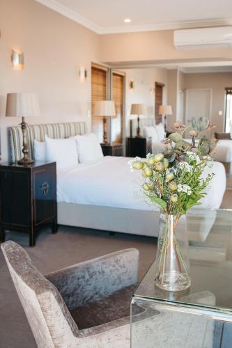 a bedroom with a bed and a vase of flowers on a table at Banksia by the Bay in Emu Point