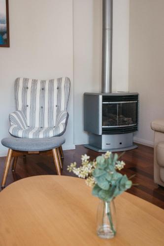 a living room with a fireplace and a chair and a table at Banksia by the Bay in Emu Point