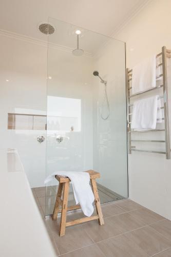 a bathroom with a glass shower and a stool at Banksia by the Bay in Emu Point