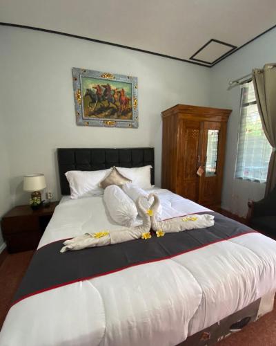 a bedroom with a large white bed with towels on it at Guest House Pondok Puspa Ayu in Kuta