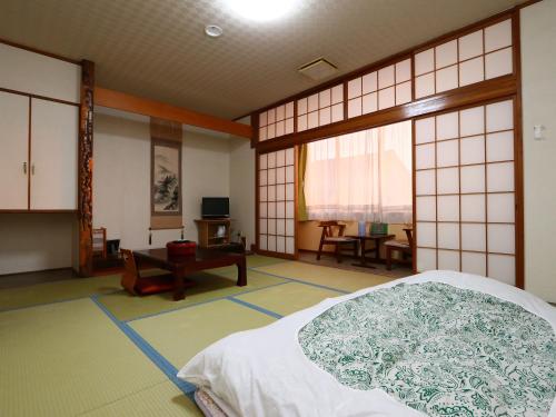Seaside Hotel Kujukuri في Sanmu: غرفة فيها سرير وطاولة فيها