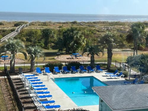 a swimming pool with lounge chairs and a beach at Sandpiper SC Luxe Oceanview Condo in Private Paradise in Oceanmarsh Subdivision