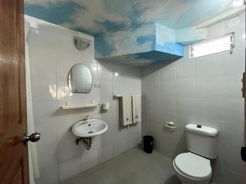 La salle de bains est pourvue de toilettes blanches et d'un lavabo. dans l'établissement Ocean Bay Beach Resort, à Dalaguete