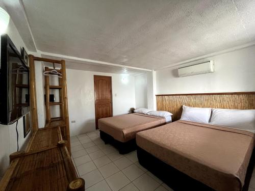 a hotel room with two beds and a television at Ocean Bay Beach Resort in Dalaguete