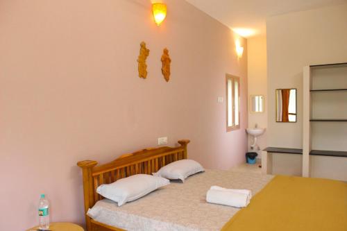 a bedroom with a bed with two pillows on it at Dwaraka Guest House in Tiruvannāmalai