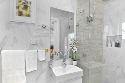 a white bathroom with a sink and a mirror at Waterfront Entertainers Haven in Toukley