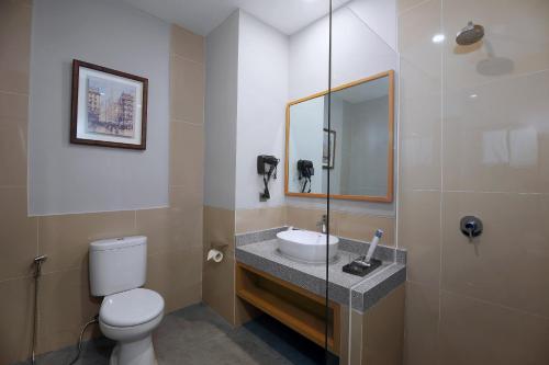 a bathroom with a sink and a toilet and a mirror at Aston Mojokerto Hotel & Conference Center in Mojokerto