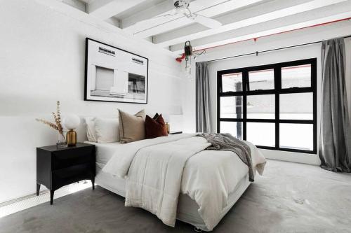 a white bedroom with a large bed and a window at New York Converted Warehouse Apartment in Richmond in Melbourne