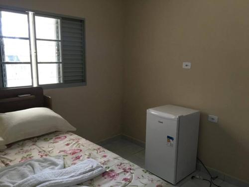 a bedroom with a bed and a small refrigerator at Hostel e Pousada Casarão - Parnaíba in Parnaíba
