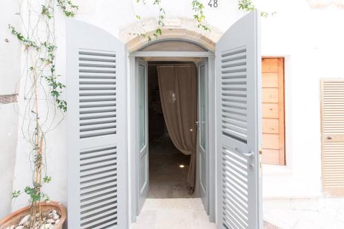 a door leading to a hallway with white shutters at Antico Mondo Rooms & Suites in Polignano a Mare