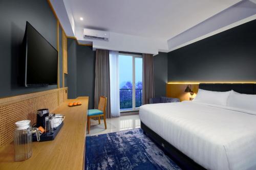 a hotel room with a bed and a desk and a television at ASTON Mojokerto Hotel & Conference Center in Mojokerto
