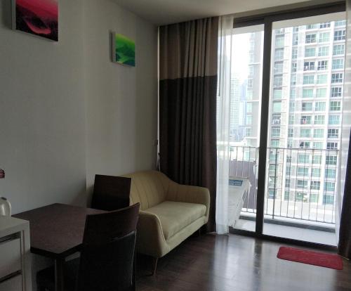 Sathon Luxury High-rise Apartment City View KingPower ,IconSiam ,BNH,Silom في بانكوك: غرفة معيشة مع أريكة وطاولة ونافذة
