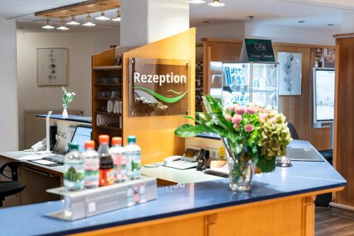 a reception desk with a vase of flowers on a counter at Hotel am Tierpark Gotha in Gotha