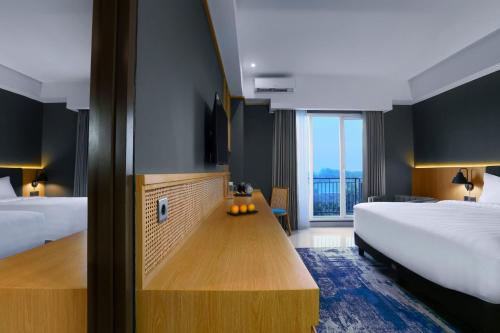 a hotel room with two beds and a wooden table at Aston Mojokerto Hotel & Conference Center in Mojokerto