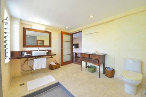 a bathroom with a sink and a toilet and a mirror at Biancas Garden Apartments Boracay in Boracay