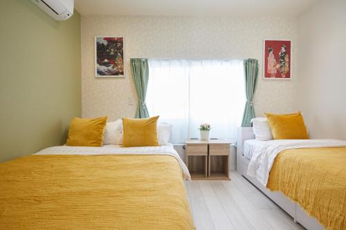 a bedroom with two beds with yellow sheets and a window at Cozy Room in東京浅草二階建の一軒家 in Tokyo