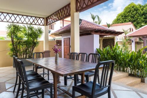a wooden table and chairs on the patio of a house at Beautiful 5BR Villa Felicity, Pool & Garden, near Naiharn in Rawai Beach