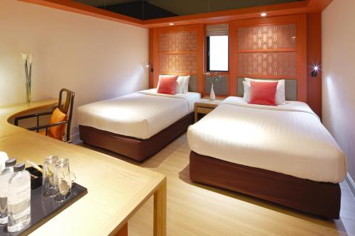a hotel room with two beds and a table at The Quarter Hualamphong by UHG in Bangkok