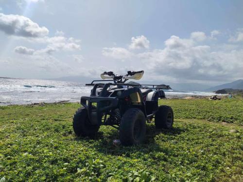 a four wheeler parked on a beach near the ocean at Nest Resort in Pagudpud