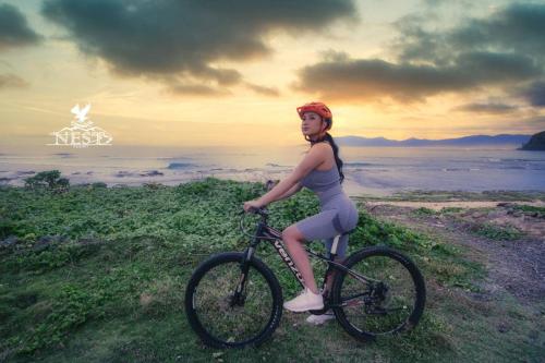 a woman riding a bike on a hill near the ocean at Nest Resort in Pagudpud