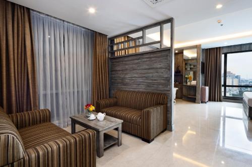 a living room with two couches and a table at Eden Star Saigon Hotel in Ho Chi Minh City
