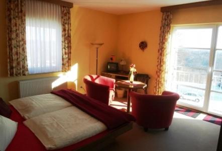 a bedroom with a bed and a table and a window at Hotel Drei Kronen in Frauenwald