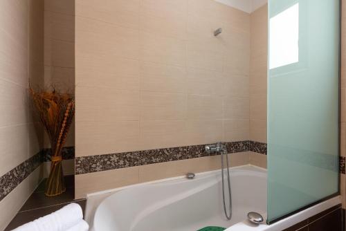 a bathroom with a bath tub with a glass shower door at Acro Villa in Afantou