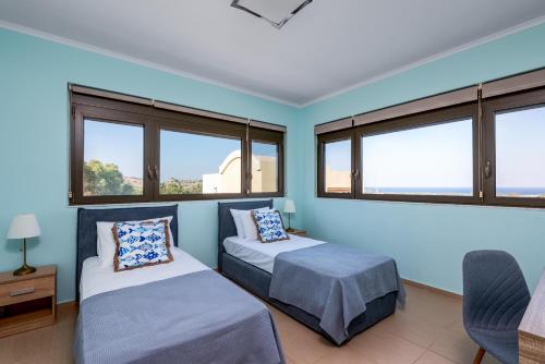 two beds in a room with windows at Acro Villa in Afantou