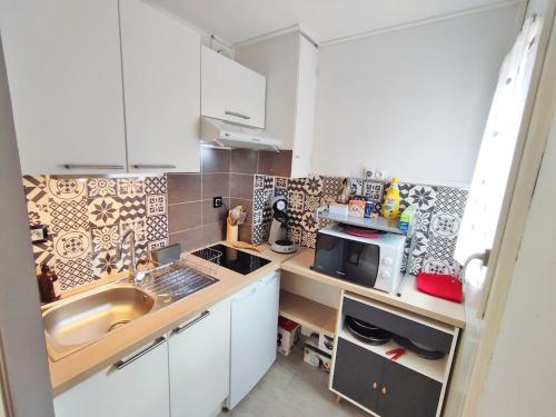 une petite cuisine avec un évier et un micro-ondes dans l'établissement Le reflet des montagnes, studio, centre Luchon, 4 personnes, à Luchon