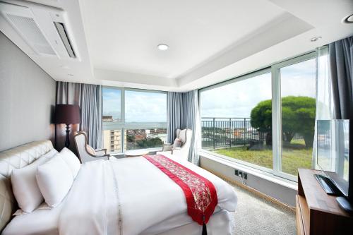 a bedroom with a bed and a large window at Bareve Hotel in Seogwipo