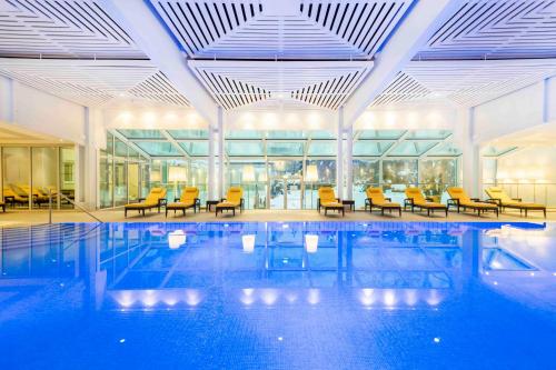 a large swimming pool with yellow chairs in a building at EUROPÄISCHER HOF Bad Gastein in Bad Gastein