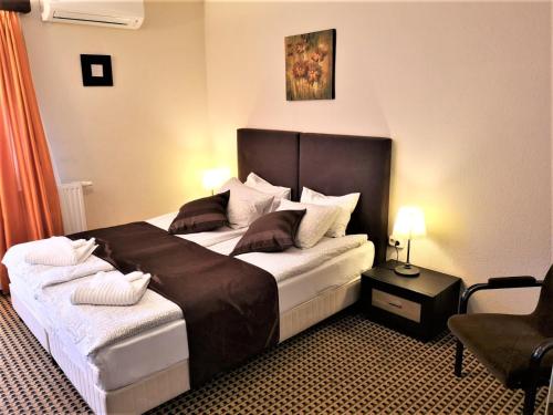 a bedroom with a large bed and a chair at Kikelet Villa in Dunakeszi