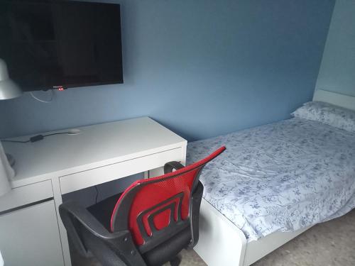 a red chair in a room with a desk and a bed at Habitació B Cal Kim in Martorell