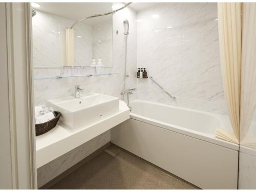a white bathroom with a sink and a bath tub at TOKYO EAST SIDE HOTEL KAIE in Tokyo