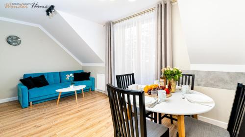 a dining room with a table and a blue couch at Wonder Home - Apartamenty położone blisko deptaka, licznych restauracji i sklepów in Karpacz
