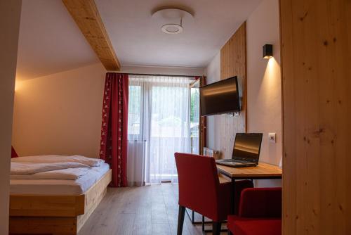 a hotel room with a bed and a desk with a laptop at Garni Siebnerhof in San Candido
