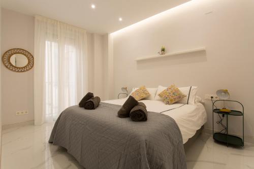 a white bedroom with a bed with towels on it at Apartamento San Isidro Centro in Granada