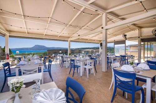 a restaurant with white tables and blue chairs at Kiani Beach Resort Family All Inclusive in Kalyves
