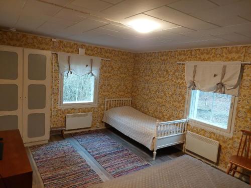 1 dormitorio con 1 cama, 2 ventanas y alfombra en Punavilla Cottage, en Eura