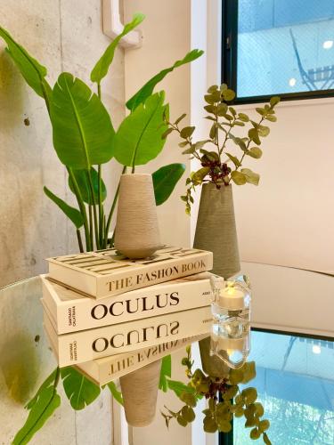 a stack of books sitting on a table with vases at Ken's Place四谷 in Tokyo