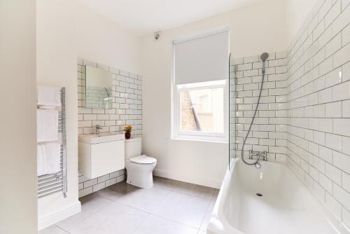 een badkamer met een bad, een toilet en een wastafel bij The Fulham Escape - Alluring 5BDR Flat in Londen