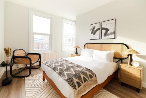 een slaapkamer met een bed en een stoel en 2 ramen bij The Fulham Escape - Alluring 5BDR Flat in Londen