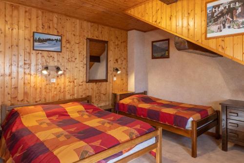 two beds in a room with wooden walls at La Rose des Vents N 3 in Châtel